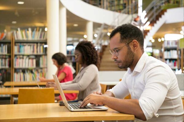 young adults working on laptops in the library
